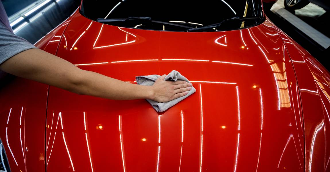 worker applying ceramic coating on red car
