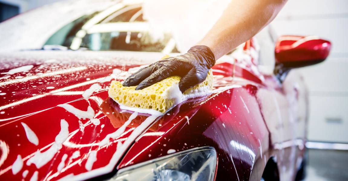 man washing red car with sponge