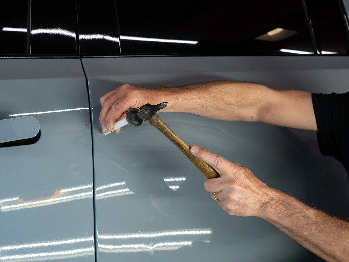 Paintless dent repair (PDR) being performed on vehicle door
