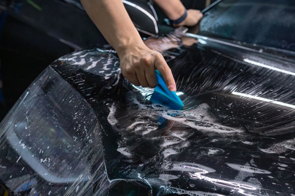 Squeegeeing slip solution during a professional PPF installation on a 2026 Tesla Model X hood at Pro-Tech Auto Shield in Wheat Ridge