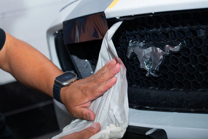 Installation of custom vinyl racing stripes on a Ford Mustang bumper at Pro-Tech Auto Shield in Wheat Ridge