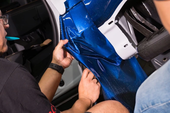 Technician applying high-end blue paint protection film to a vehicle for a custom look in the Denver area