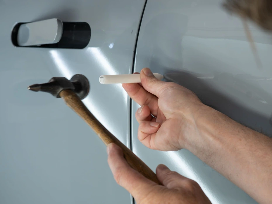 Technician using a PDR reflection board to precisely locate and remove a dent in Wheat Ridge