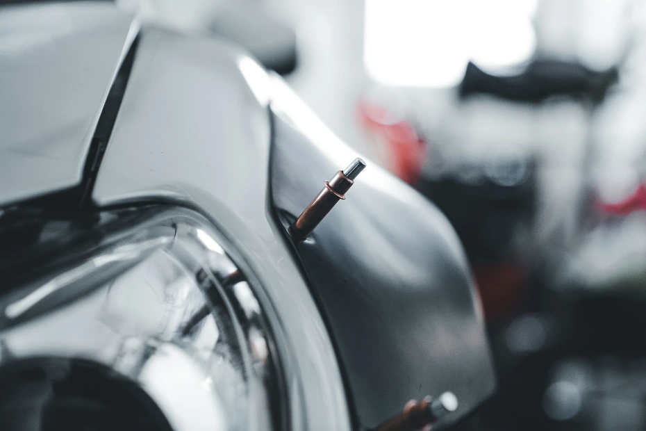 Removing a door ding from a vehicle fender using specialized PDR rods