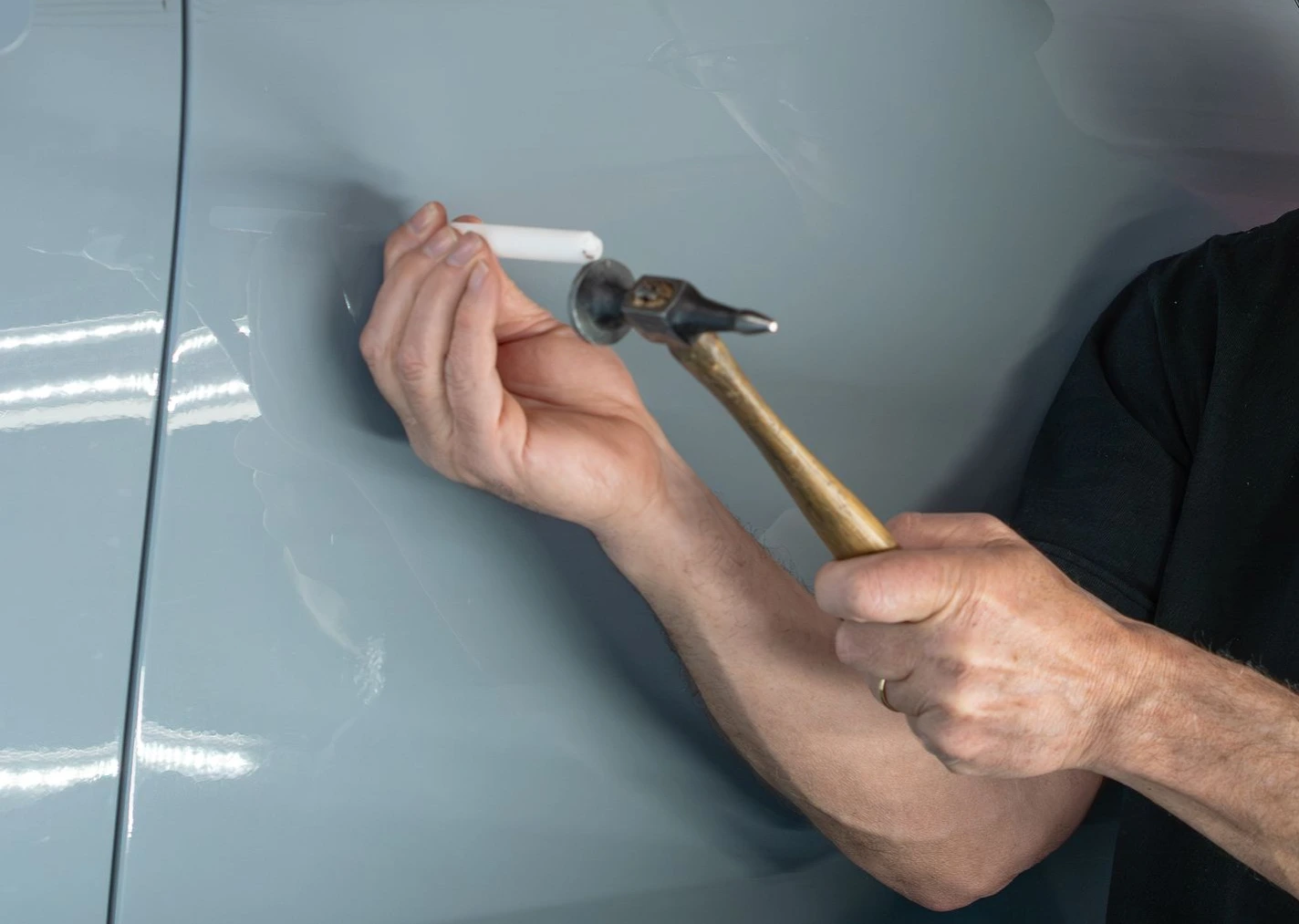 Using a specialized PDR knockdown tool to perfectly level a high spot without damaging the factory paint