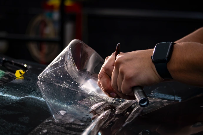 Close up detail shot of a PPF installer cutting paint protection film on a vehicle