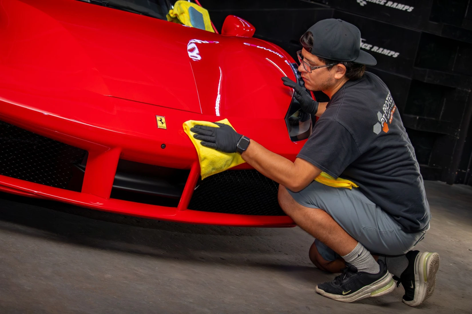 Ceramic coating installer wiping excess from a red 2024 Porsche Carrera 911 bumper and hood