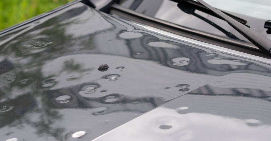 black car engine hood with hail damage