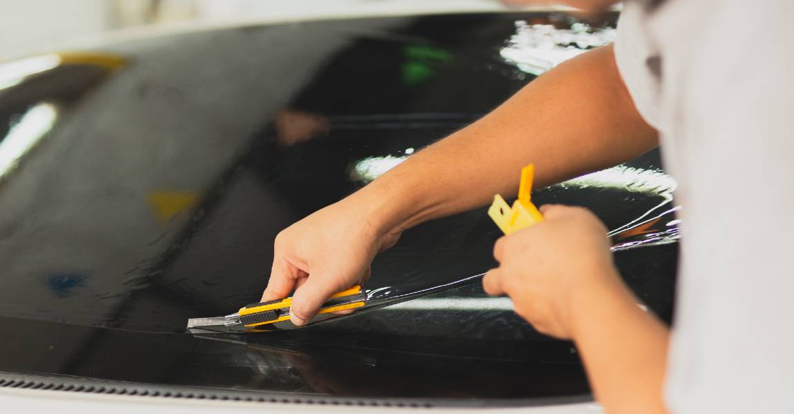 man applying window tint to car window