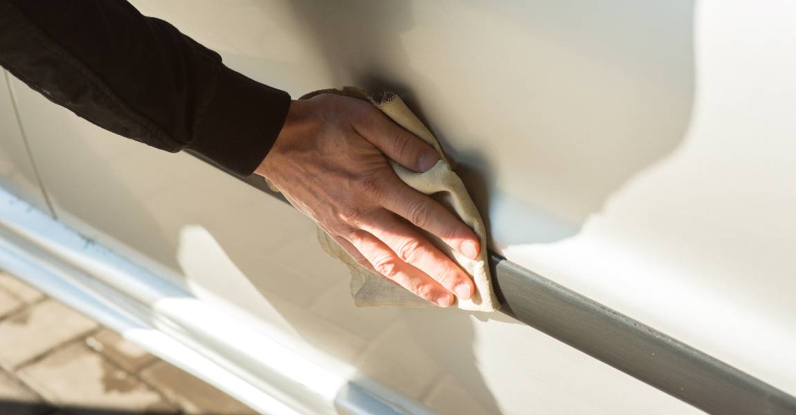 man spot cleaning white car close up