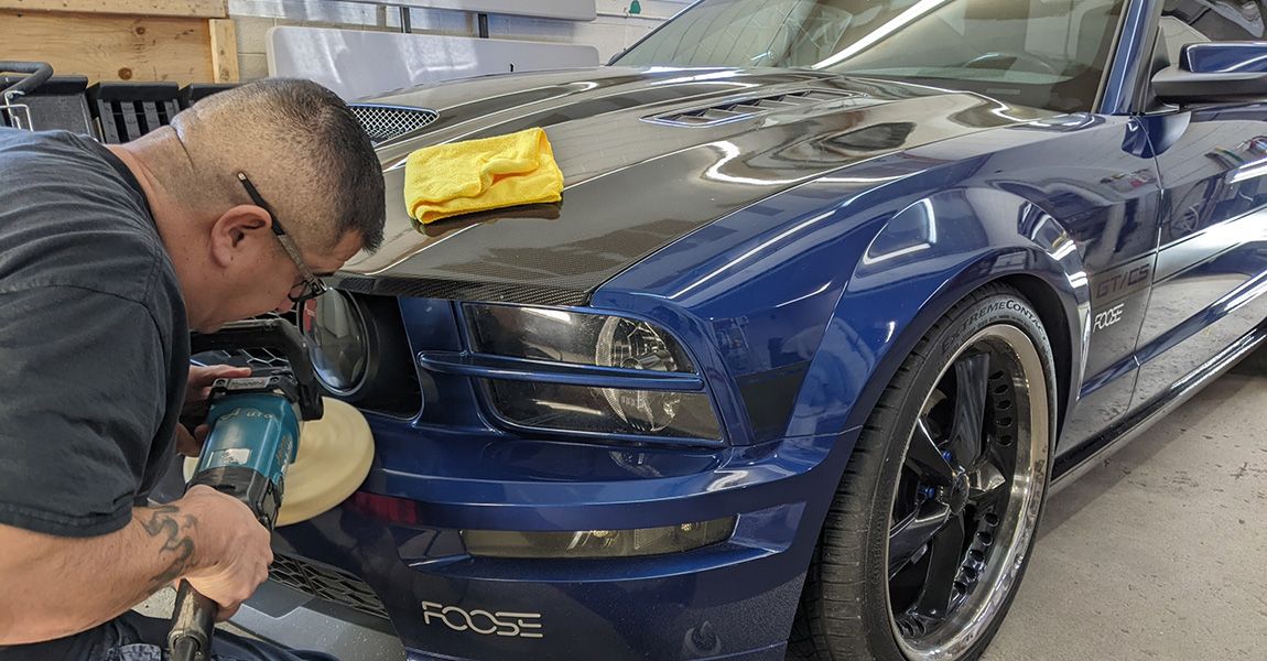 professional nano ceramic coating being applied to front of blue mustang sports car